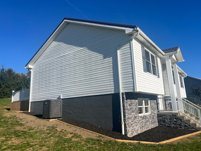 view of side of home featuring central air condition unit and a yard