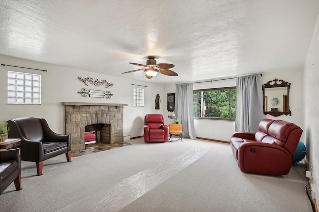 sitting room with a stone fireplace, carpet floors, and ceiling fan