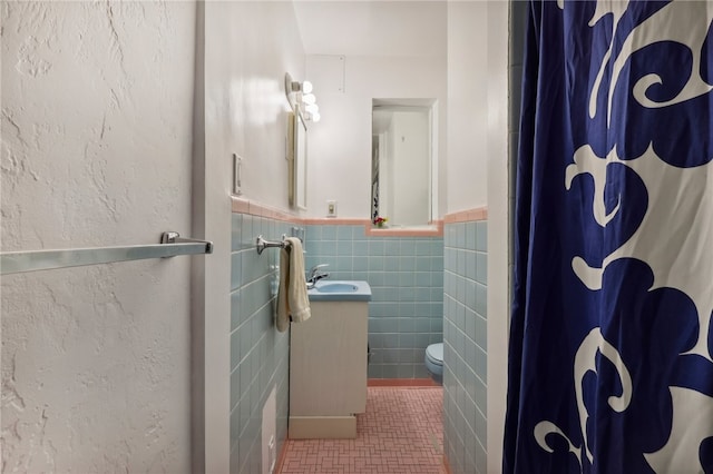 bathroom featuring tile patterned floors, toilet, curtained shower, tile walls, and vanity