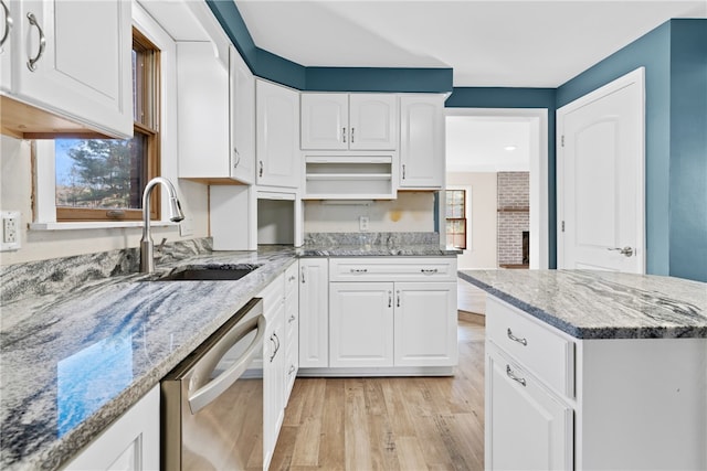 kitchen featuring white cabinets, light stone counters, stainless steel dishwasher, light hardwood / wood-style floors, and sink