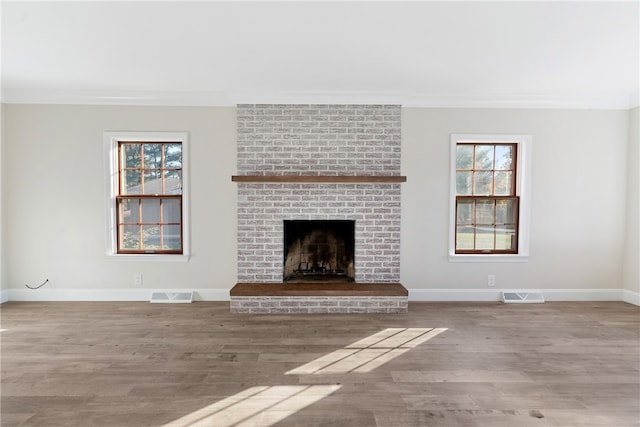 unfurnished living room featuring crown molding, a brick fireplace, and hardwood / wood-style flooring