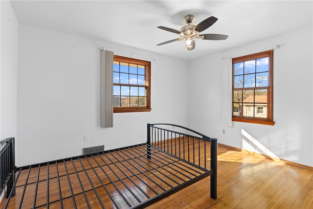 bedroom with hardwood / wood-style floors, multiple windows, and ceiling fan