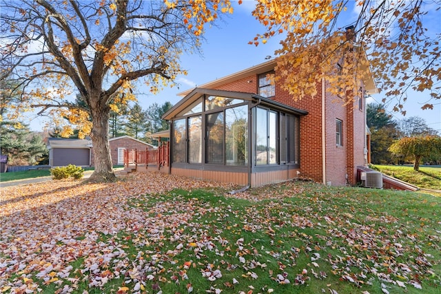 view of side of home featuring central AC, a yard, and a sunroom