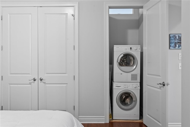 laundry room featuring dark wood-type flooring and stacked washer and clothes dryer