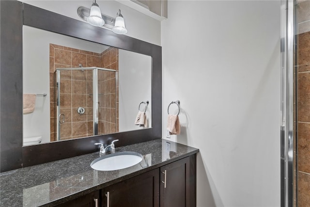 bathroom with a shower with door, vanity, and toilet