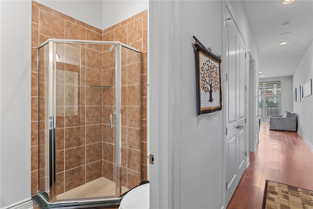 bathroom with a shower with door, toilet, and hardwood / wood-style floors