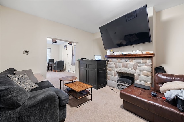 living room with a stone fireplace and light carpet