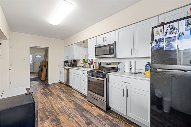 kitchen with dark hardwood / wood-style floors, stainless steel appliances, backsplash, sink, and white cabinetry