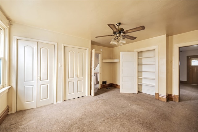 unfurnished bedroom featuring ceiling fan, carpet flooring, and two closets