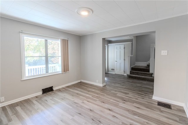 spare room with ornamental molding and light wood-type flooring