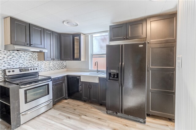 kitchen with decorative backsplash, black appliances, sink, and light wood-type flooring