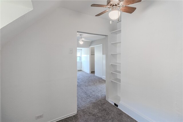 hallway featuring dark carpet, lofted ceiling, and built in features