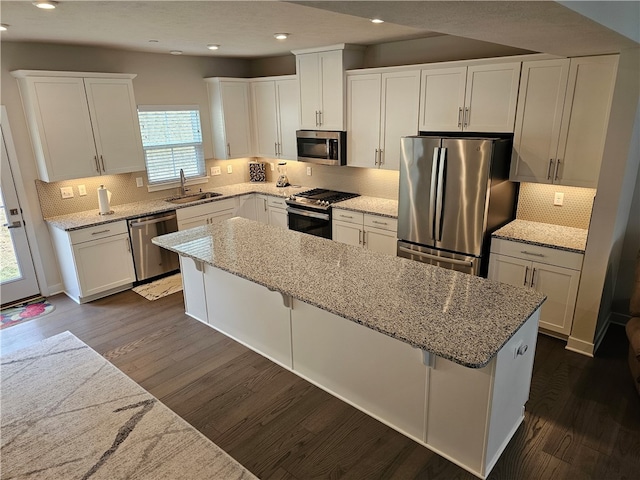 kitchen with a kitchen island, appliances with stainless steel finishes, dark hardwood / wood-style flooring, a kitchen bar, and sink