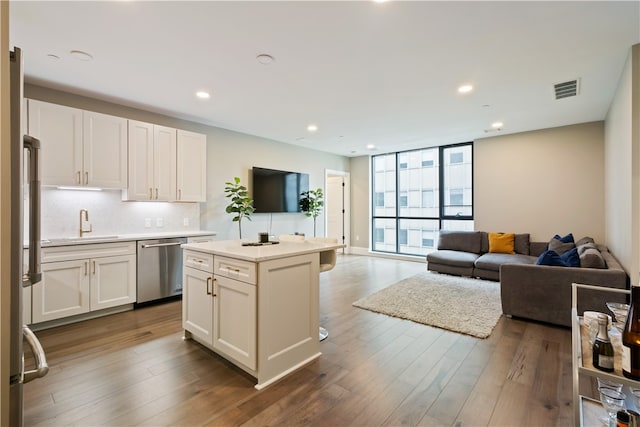 kitchen featuring white cabinets, stainless steel dishwasher, hardwood / wood-style floors, and a kitchen island