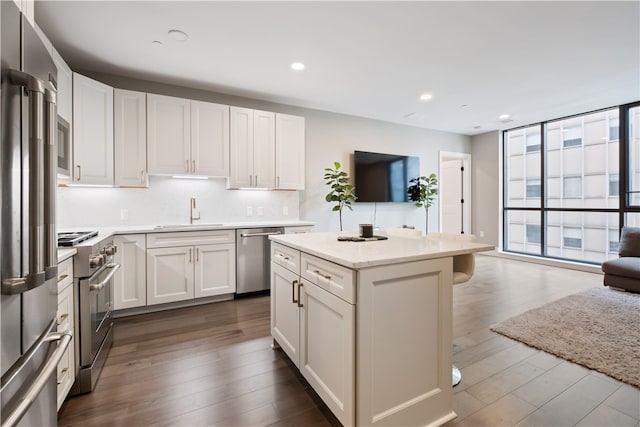 kitchen with white cabinets, dark hardwood / wood-style flooring, a kitchen island, high quality appliances, and sink