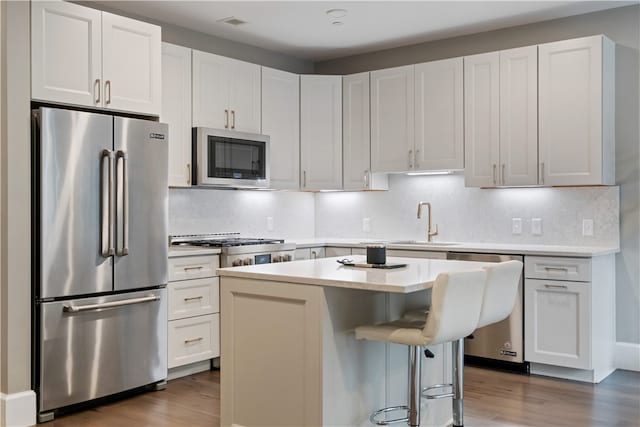 kitchen featuring appliances with stainless steel finishes, white cabinets, hardwood / wood-style flooring, and a kitchen island