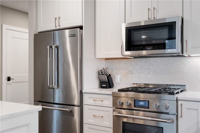 kitchen with decorative backsplash, white cabinets, and premium appliances