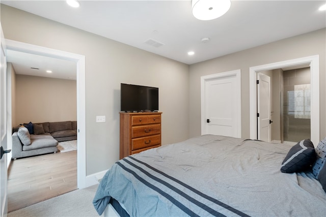 bedroom featuring connected bathroom and light wood-type flooring