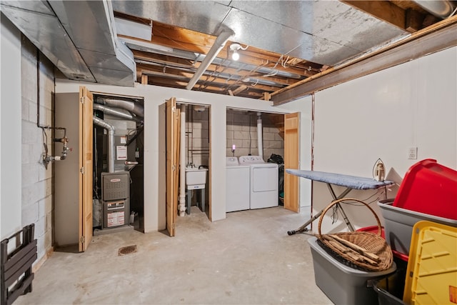 basement with sink, heating unit, and washer and clothes dryer