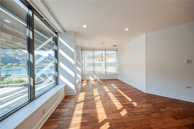 unfurnished room with hardwood / wood-style flooring, a chandelier, and plenty of natural light