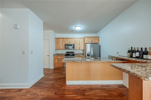 kitchen featuring appliances with stainless steel finishes, sink, stone countertops, kitchen peninsula, and dark wood-type flooring