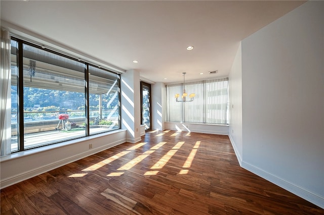 spare room featuring a notable chandelier and dark hardwood / wood-style flooring