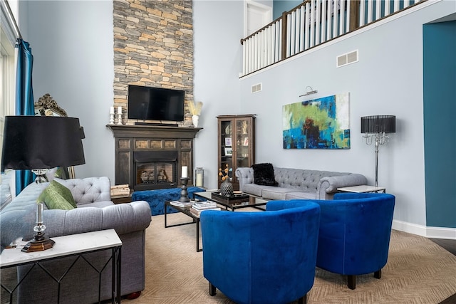 living room with a stone fireplace and a towering ceiling