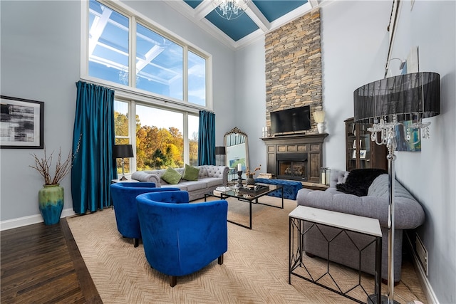 living room with a stone fireplace, ornamental molding, hardwood / wood-style floors, and a towering ceiling