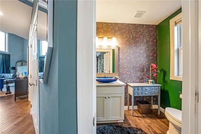 bathroom featuring toilet, hardwood / wood-style floors, and a healthy amount of sunlight