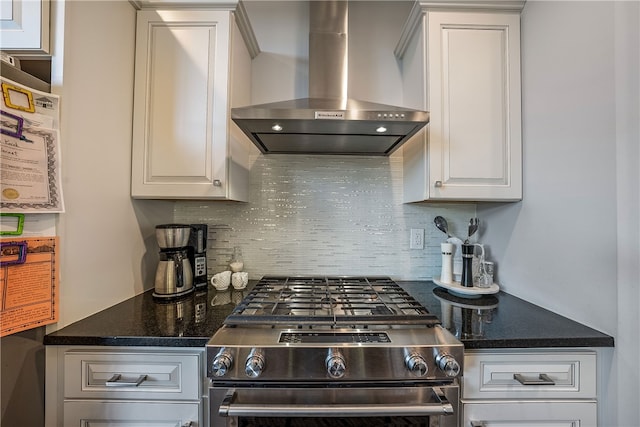 kitchen with wall chimney exhaust hood, backsplash, white cabinetry, and high end stove