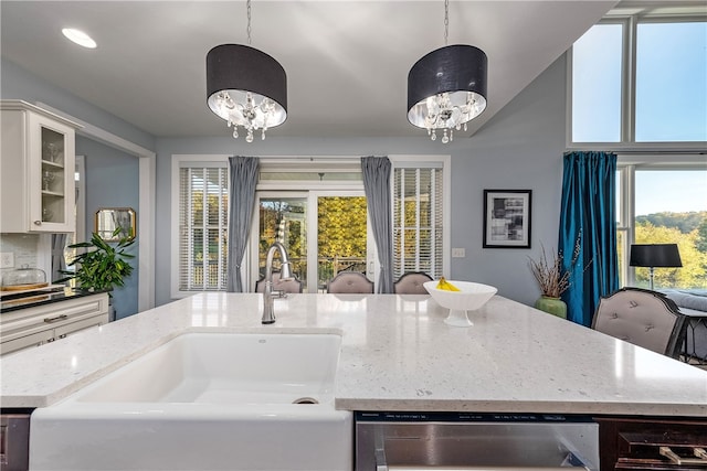 kitchen with sink, decorative light fixtures, a center island with sink, and white cabinets