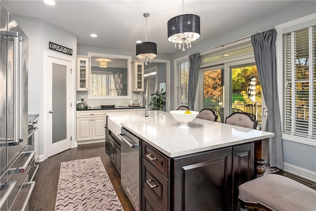 kitchen featuring dark hardwood / wood-style flooring, stainless steel appliances, decorative light fixtures, dark brown cabinetry, and a center island