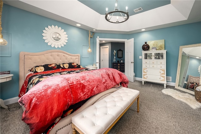 bedroom with an inviting chandelier, a tray ceiling, and carpet