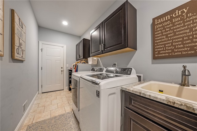 washroom with sink, washer and dryer, light tile patterned floors, and cabinets