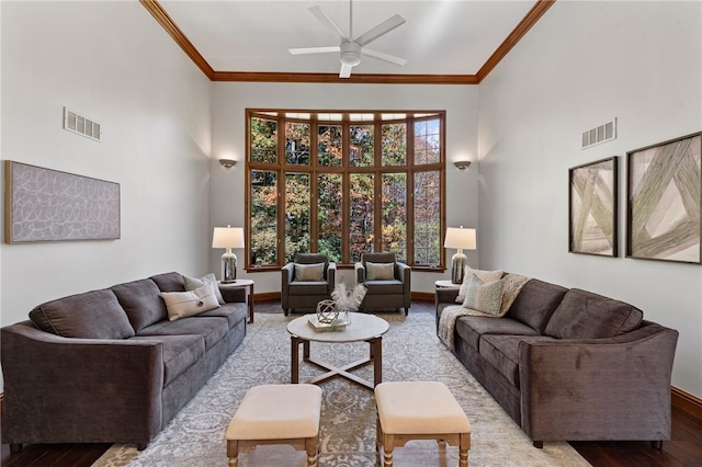 living room with ornamental molding, a high ceiling, light wood-type flooring, and ceiling fan