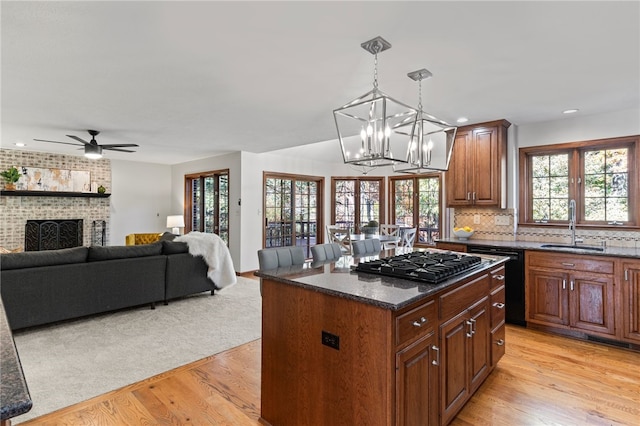 kitchen featuring stainless steel gas cooktop, light hardwood / wood-style flooring, black dishwasher, and a kitchen island