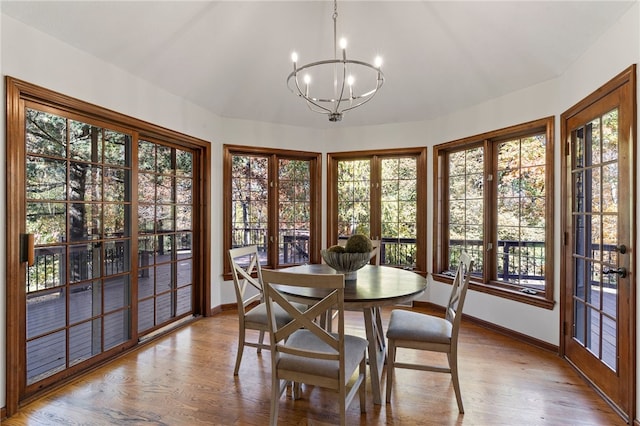 dining area with a wealth of natural light, french doors, hardwood / wood-style floors, and a chandelier