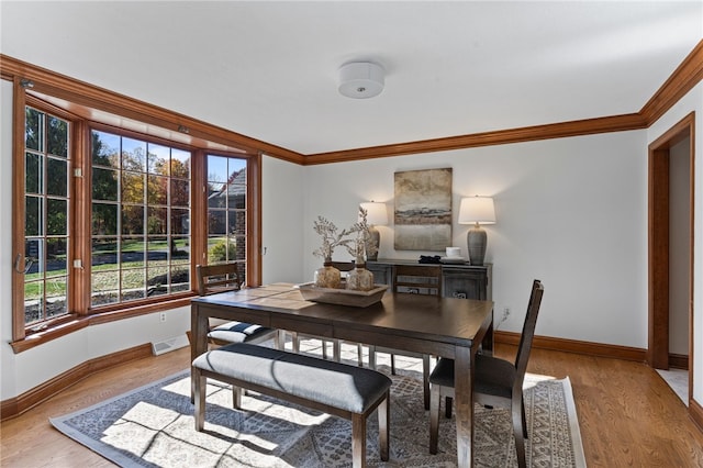 dining area with ornamental molding and light wood-type flooring