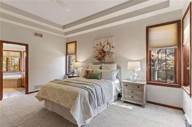 bedroom featuring ensuite bathroom, multiple windows, light colored carpet, and ceiling fan