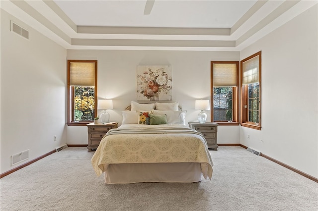 carpeted bedroom with a raised ceiling and ceiling fan