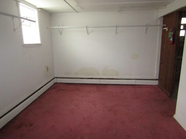 walk in closet featuring a baseboard heating unit and dark colored carpet