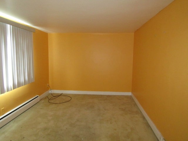 carpeted spare room featuring a baseboard radiator