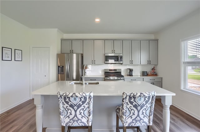 kitchen with wood-type flooring, appliances with stainless steel finishes, gray cabinetry, and a healthy amount of sunlight