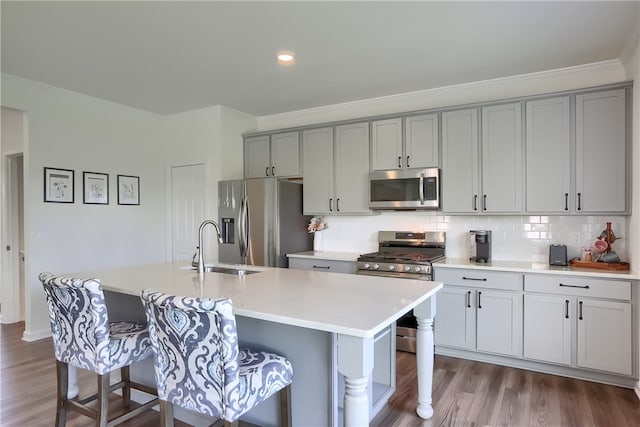 kitchen featuring stainless steel appliances, a breakfast bar, and a center island with sink