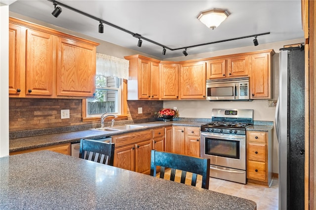 kitchen featuring backsplash, sink, stainless steel appliances, and rail lighting