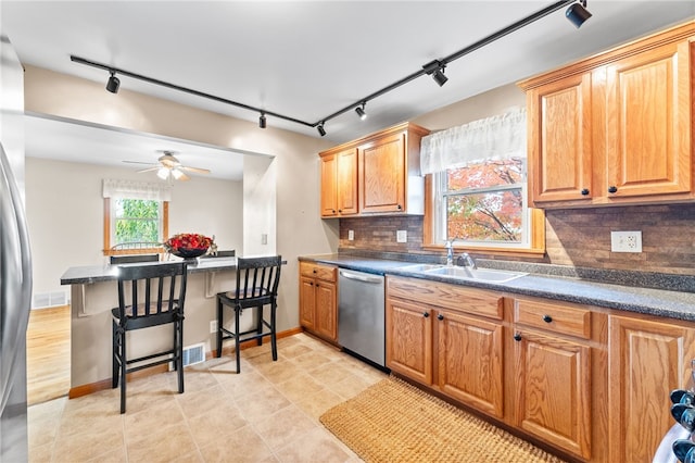 kitchen with decorative backsplash, track lighting, stainless steel dishwasher, and sink