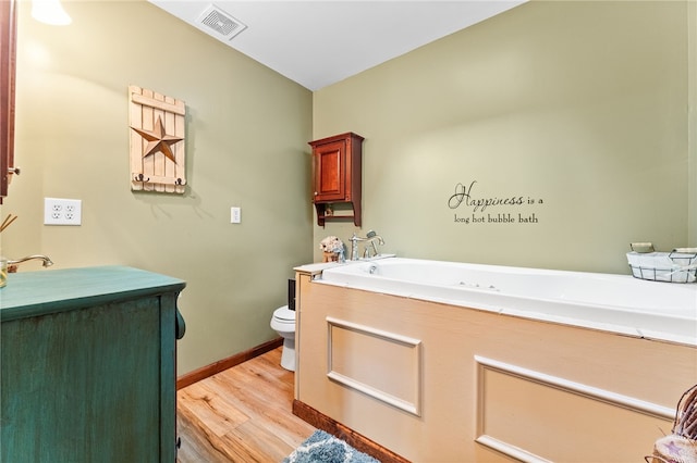 bathroom with hardwood / wood-style floors, toilet, and a bathing tub