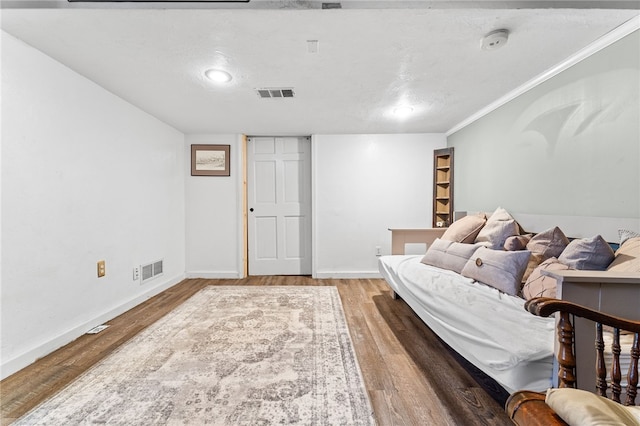 sitting room with crown molding, a textured ceiling, and hardwood / wood-style floors