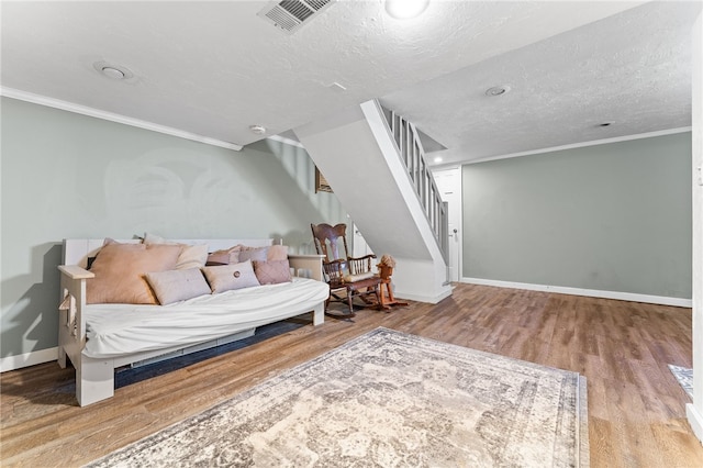 living room with light hardwood / wood-style floors, crown molding, and a textured ceiling