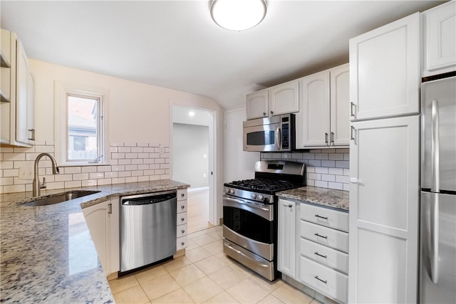 kitchen with backsplash, white cabinetry, light stone countertops, sink, and stainless steel appliances